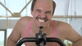 Closeup, funny bald man is training on an exercise bike, smiling Royalty Free Stock Photo