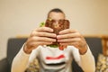 Closeup funny blurred protrait of young man hold bitten sandwich by his two hands. Sandwich in focus. light background