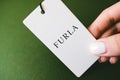 Closeup of FURLA brand logo label on green background .