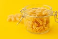 Closeup of fusilli pasta in galss jar on yellow background
