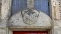 Closeup of the Gable Stone for the Blacksmith`s Guild above a red door, Waag House, Amsterdam, The Netherlands