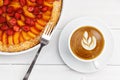 Closeup galette with apricots and strawberries. Homemade pastry and cup of coffee on white wooden table. Royalty Free Stock Photo