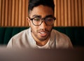 .. Closeup of geeky young indian man wearing glasses while reading something interesting and sitting inside. Man wearing