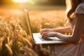 closeup on girl farmer hands using laptop computer in the agricultural wheat field at sunset