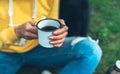 Closeup girl holding in hands cup of hot tea on green grass in outdoors nature park, beautiful woman hipster enjoy drinking cup Royalty Free Stock Photo