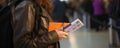 In a closeup, a girl holds passports and a boarding pass anxiously