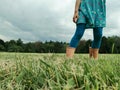 Closeup of girl legs feet in rain boots walking on meadow. Freedom, innocence and adolescense concept. Summer fun outdoors Royalty Free Stock Photo