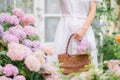 Closeup of a girl in a white, dress holding a basket with colorful hydrangeas, walking outdoors