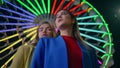 Closeup girls rest ferris wheel at night. Two fashion models pose at illuminated Royalty Free Stock Photo