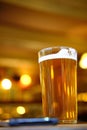 Closeup of a glass of beer on the table under the lights with a blurred background Royalty Free Stock Photo