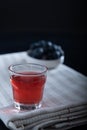 Closeup of a glass of blueberry juice on top of a kitchen towel. Blueberries in the background Royalty Free Stock Photo