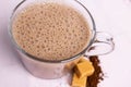 Closeup of a glass of Caramel Macchiato on awhite surface with coffee beans and caramel candies