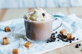 Closeup of a glass of Caramel Macchiato on awhite surface with coffee beans and caramel candies