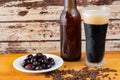 Closeup of a glass of cold dark beer, olives, and malted barley grains on the table Royalty Free Stock Photo