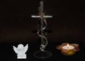 Closeup of glass cross next to the angel souvenir and candle against a black background Royalty Free Stock Photo