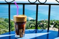 Closeup of a glass of iced coffee on background of a beautiful view of the Aegean sea