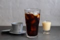 Closeup of a glass of iced coffee, condensed milk and a Vietnamese coffee filter Royalty Free Stock Photo