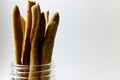 Glass jar full of Italian grissini on a white background