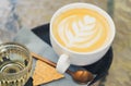 Closeup glass of latte art coffee tulip shape on glass table with flower background