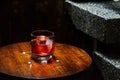 Closeup glass of negroni cocktail with ice at bar table at porch stairs background