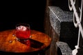 Closeup glass of negroni cocktail with ice at bar table at porch stairs background. Loft style