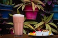 Closeup of a glass of a strawberry milkshake served with a plate of fruits and pastry Royalty Free Stock Photo