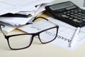 Closeup of glasses, blank paper for marketing plan, pile of documents, calculator on the desk Royalty Free Stock Photo