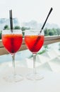 Closeup glasses of cocktail decorated with oranges on the table. Colorful pink soft drinks with ice and straws in a cafe