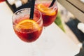 Closeup glasses of cocktail decorated with oranges on the table. Colorful pink soft drinks with ice and straws in a cafe