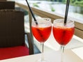 Closeup glasses of cocktail decorated with oranges on the table. Colorful pink soft drinks with ice and straws in a cafe