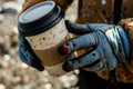 closeup of gloved hands holding a spillproof astronaut coffee cup