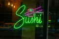 Closeup of a glowing neon light signboard of a sushi bar on a glass wall Royalty Free Stock Photo