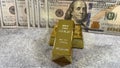 Closeup of a gold with the pile of American dollars banknotes in the background