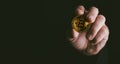 Closeup of golden bitcoin BTC cryptocurrency in hand over dark black background