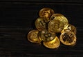 Closeup golden coin with bitcoin logo. Leader in cryptocurrency Bitcoin BTC on a top of coins against black wooden surface. Pile