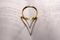 Closeup of a golden engagement ring forming a shadow of a heart on the open holy bible Royalty Free Stock Photo