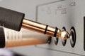 Closeup of golden TRS phone jack audio connector next to audio device Royalty Free Stock Photo
