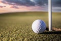 Closeup of golf ball near the target hole on green grass Royalty Free Stock Photo