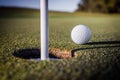 Closeup of golf ball near the target hole on green grass Royalty Free Stock Photo