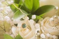 Closeup of a gorgeous gold and emerald necklace for a bride at a wedding with white roses beside it