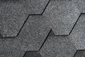 Closeup of gray asphalt roof shingles texture. Roof covered by hexagonal soft shingles or tiles. Abstract background