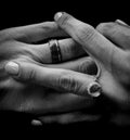Closeup grayscale shot of a couple holding hands with rings on their fingers. Royalty Free Stock Photo