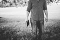 Closeup grayscale shot of a male holding the bible with a blurred background Royalty Free Stock Photo