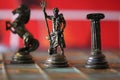 Closeup of Greek mythology chess pieces on the board with a red blurry background