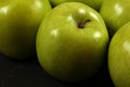 Closeup of green apples on black board, detailed photo - texture on apple skin visible