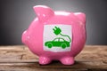 Closeup Of Green Electric Car On Pink Piggybank