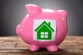 Closeup Of Green Paper House On Pink Piggybank