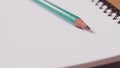 Closeup of a green pencil on a notebook. Notepad open on a blank page on the table Royalty Free Stock Photo