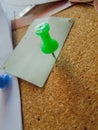 Closeup of a green pin pinning a paper with a cork pad underneath