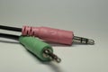 Closeup of green and pink headphone and microphone splitter cable isolated on a white background